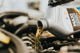 Engine oil being poured into a car engine for maintenance.