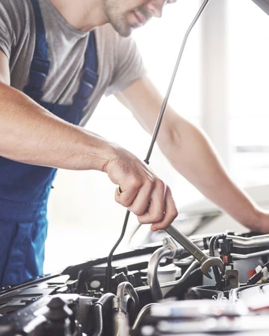 Skilled mechanic inspecting car engine at Fedora Tire & Oil LLC.