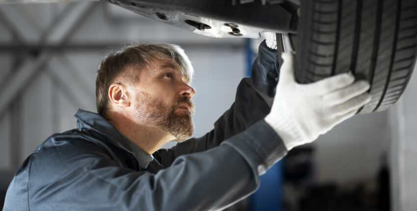 Auto mechanic inspecting a car tire for wear and safety.