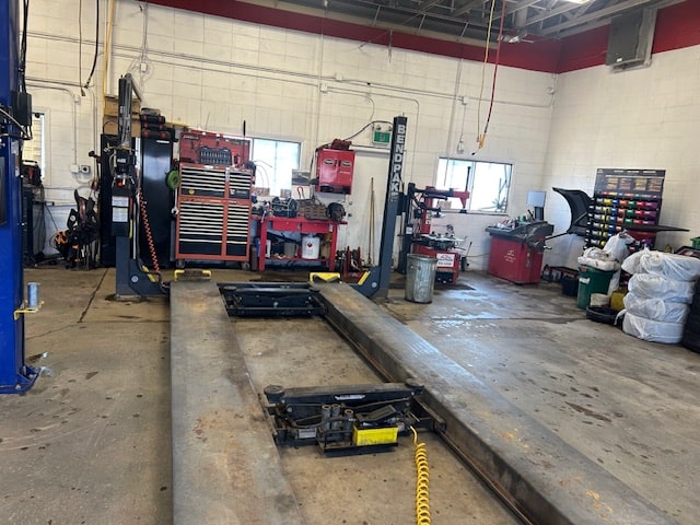 Auto repair shop with vehicle lift and various tools for car maintenance and repairs.
