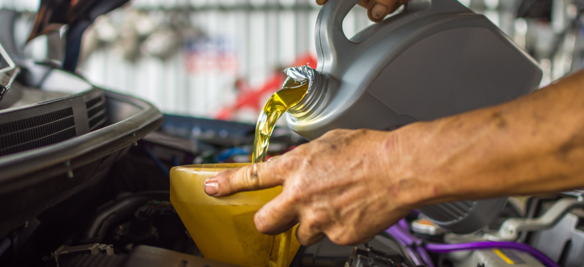 Engine oil being poured into a car engine during maintenance.