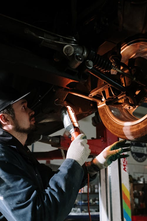 Automotive mechanic inspecting brake system under vehicle.