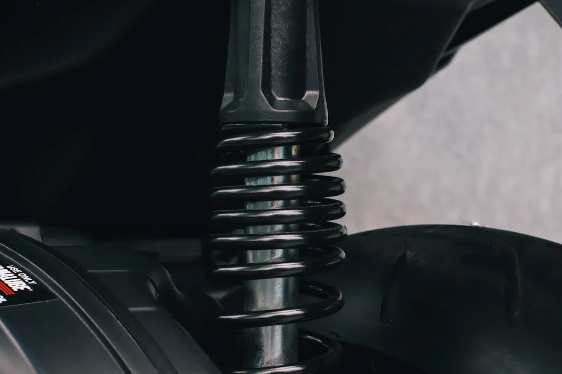 Close-up of motorcycle suspension system showing coil spring and shock absorber.