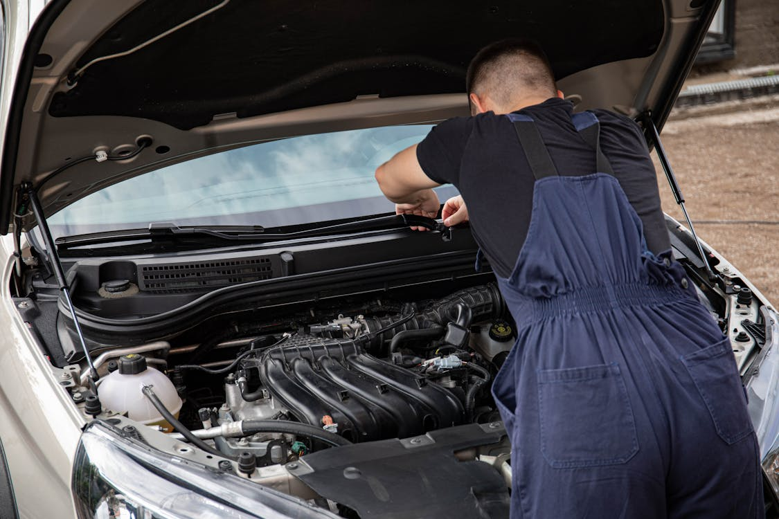 Skilled mechanic inspecting car engine for repairs at First Class Car Care.