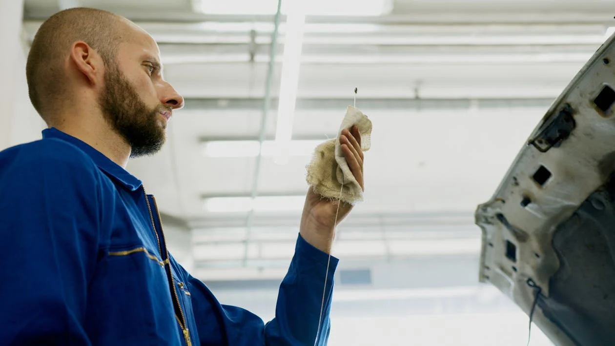 Professional auto mechanic inspecting a vehicle engine for maintenance or repair.