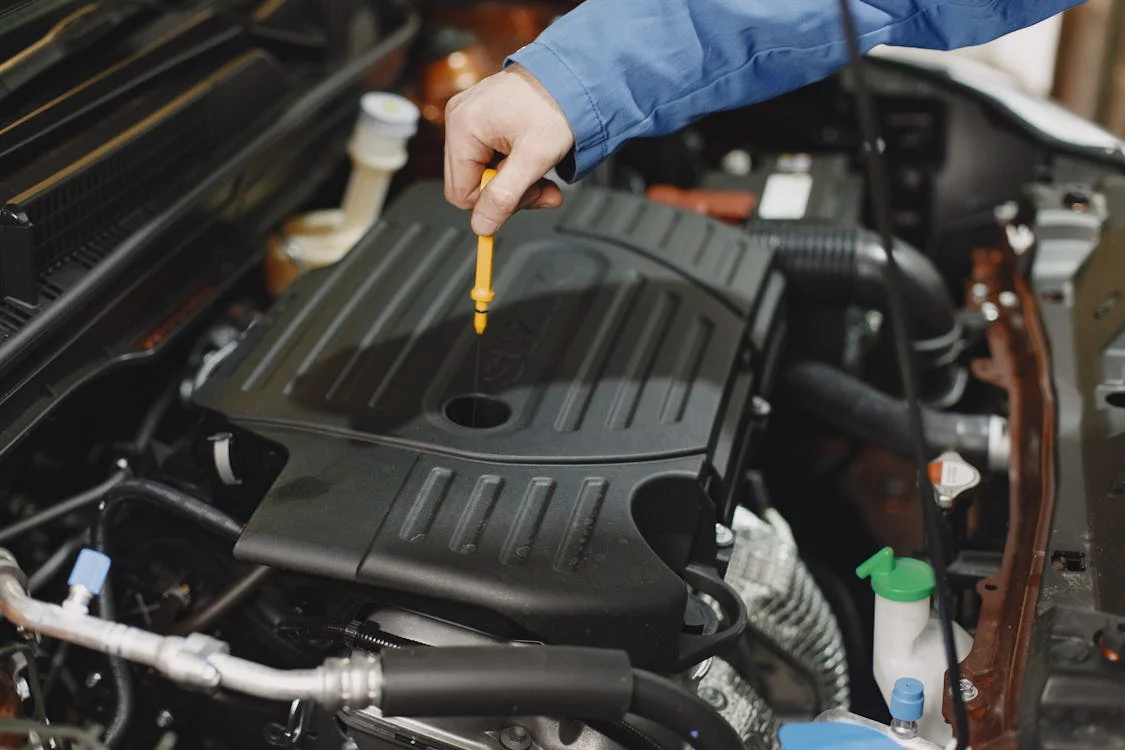 Technician checking engine oil level during car maintenance at First Class Car Care Repair.