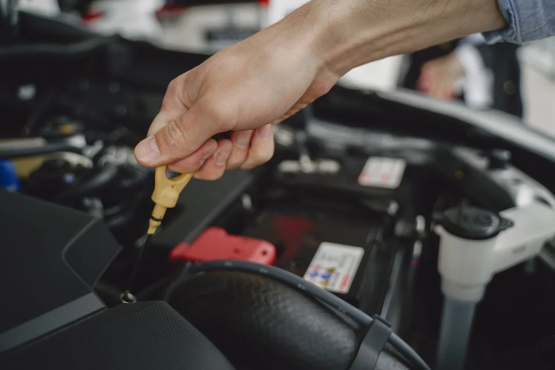 Mechanic performing engine oil change in a car engine at auto repair shop.
