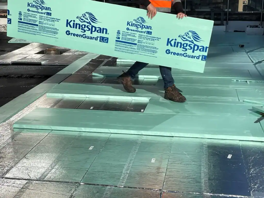 Durable Kingspan GreenGuard insulation being installed on a building roof for energy efficiency.