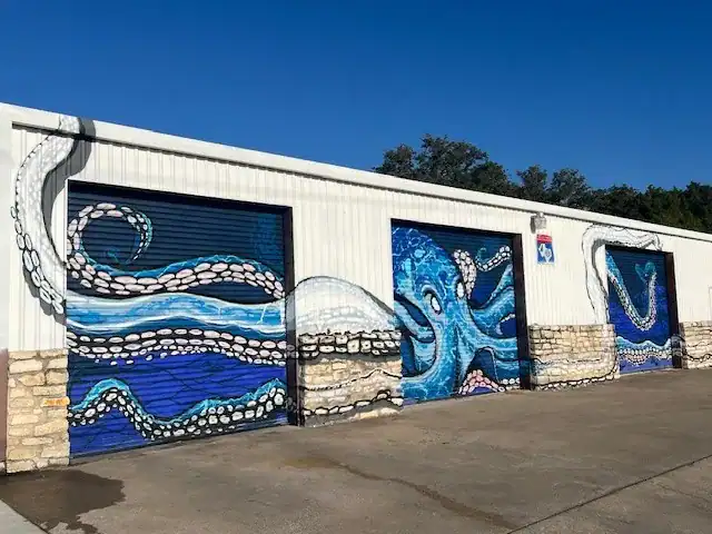 Vivid octopus mural painted on garage doors, featuring blue and white hues with ocean themes.