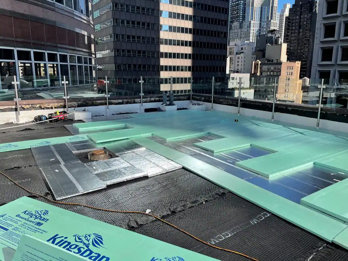 Construction site of a rooftop swimming pool with view of city skyline.