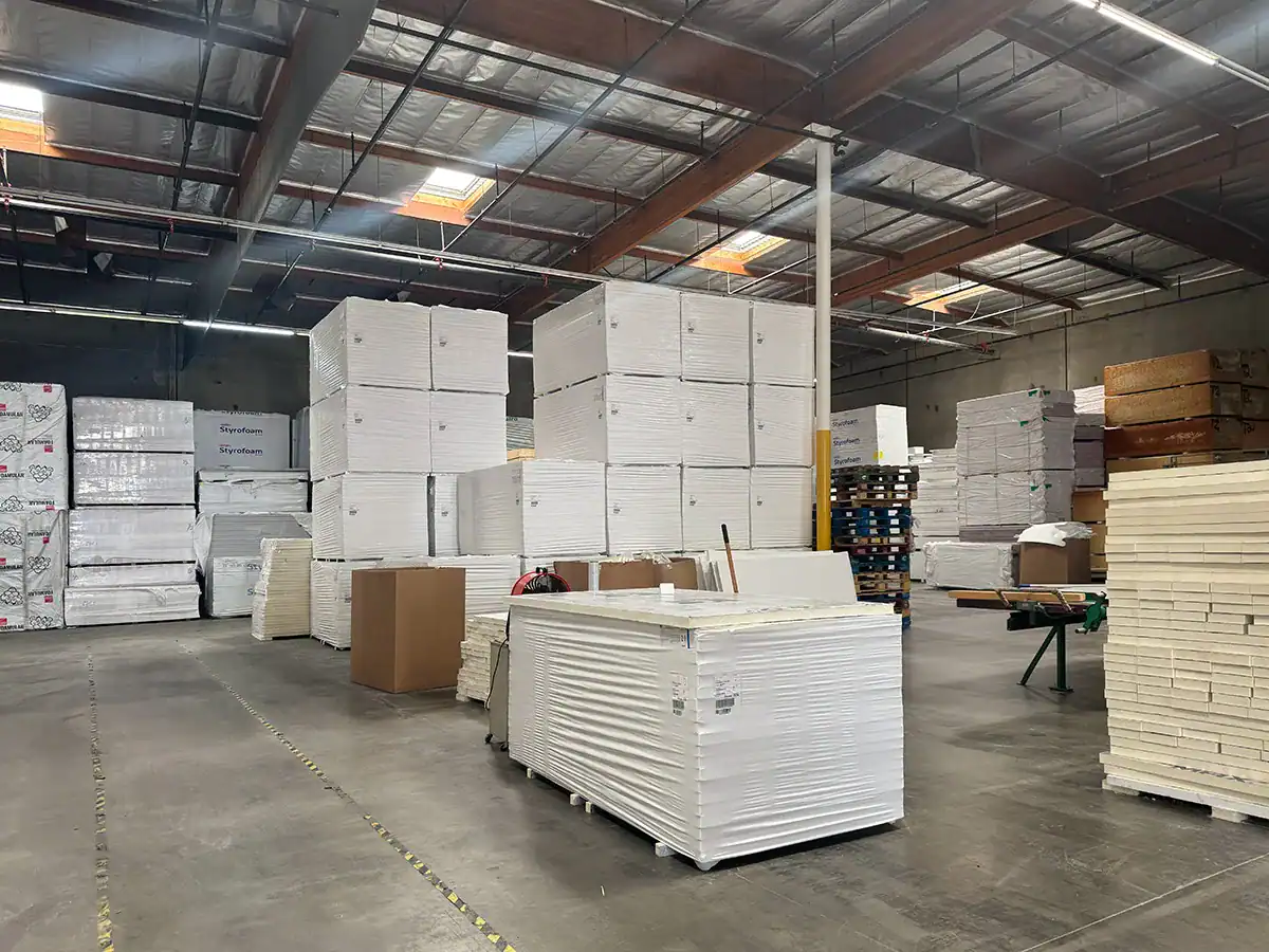 Warehouse filled with large stacks of foam boards and packaging supplies.