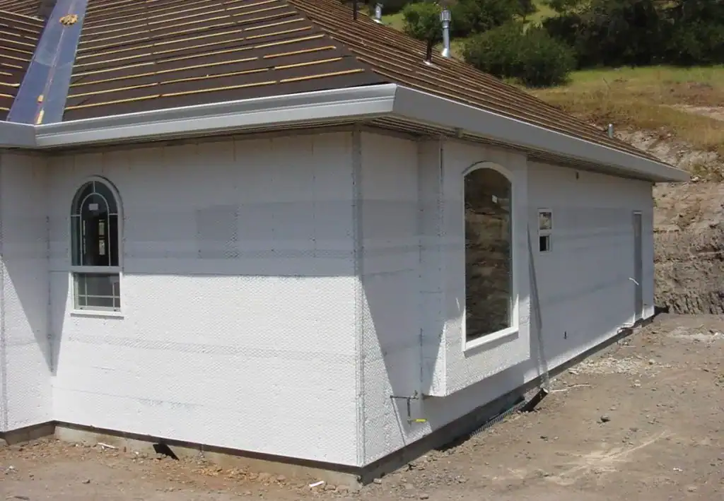 House exterior showing new insulation and window openings during construction.