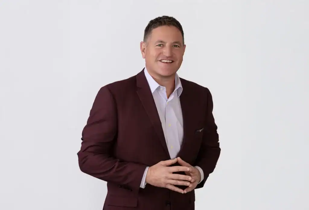 Executive in a maroon suit smiling confidently.