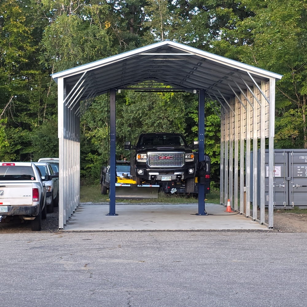 Vehicle lift under metal carport at Forrest Howes Auto Repair.