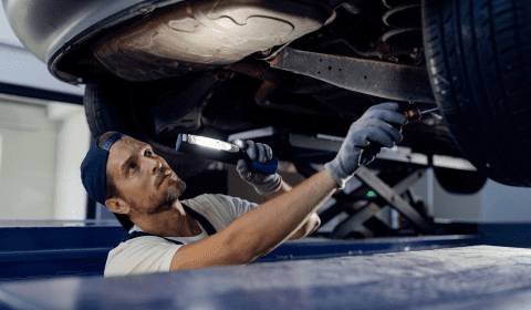 Auto repair technician inspecting vehicle underside at Franconia Auto Care.