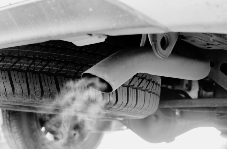 Vehicle exhaust system being inspected during engine auto service.