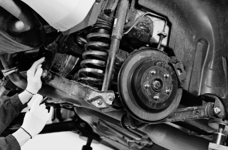 Vehicle suspension system being inspected and serviced by a mechanic.
