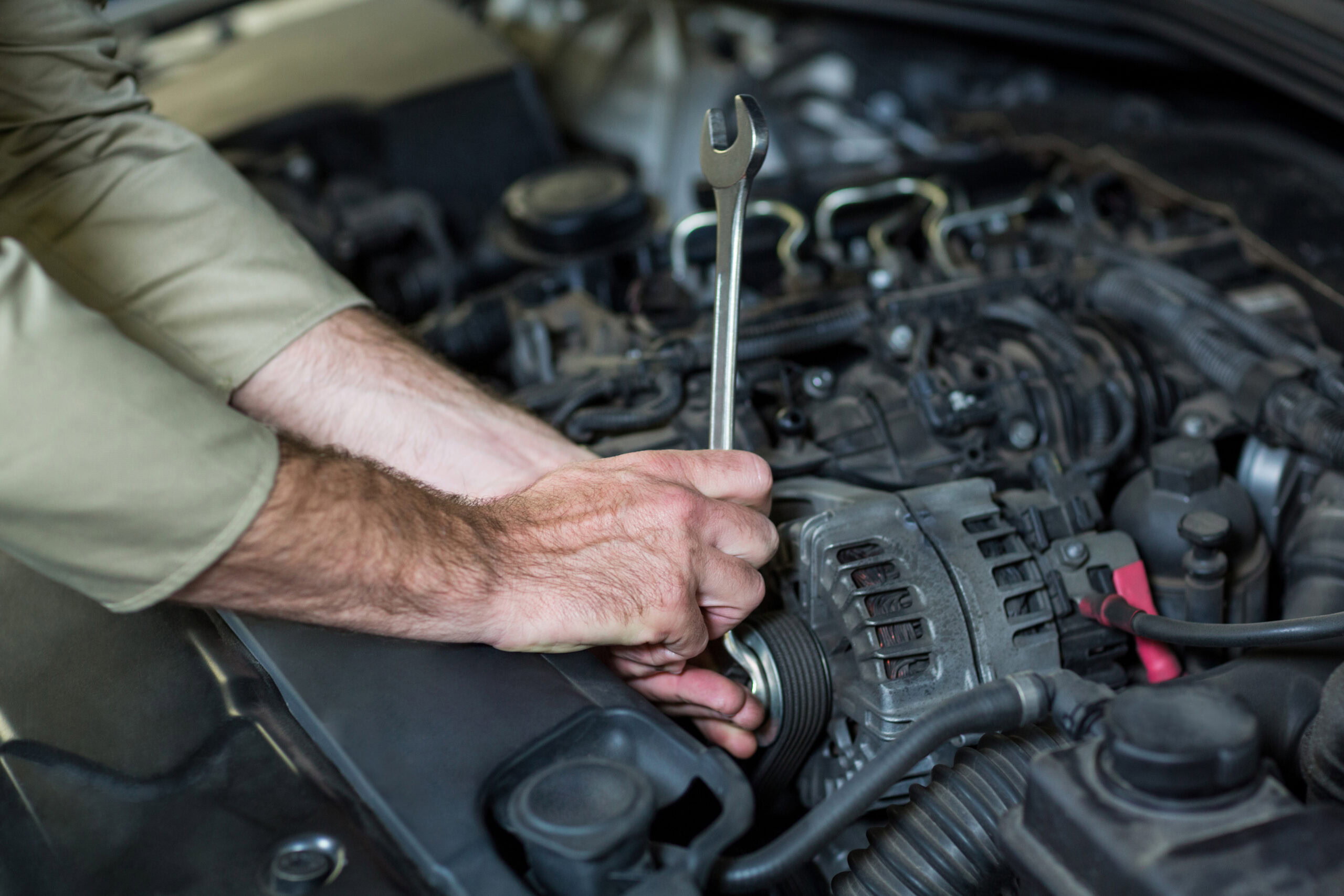 Hands of mechanic servicing a car in repair garage