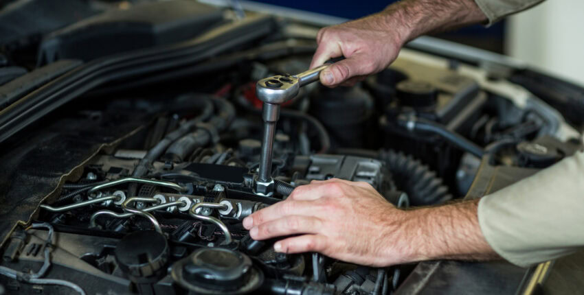 Mechanic inspecting car engine for winter maintenance and safety checks.