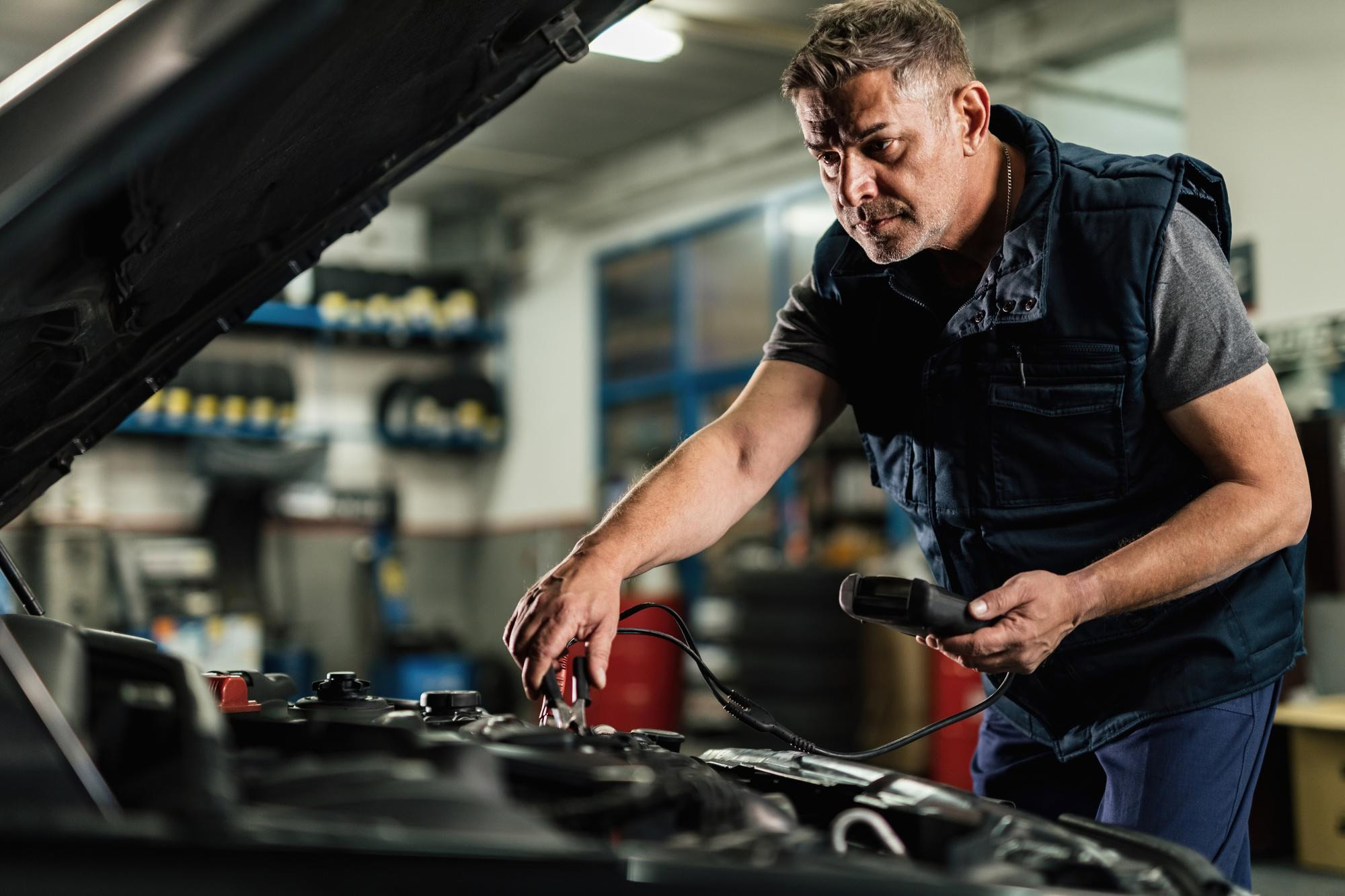 Expert mechanic checking car's battery using diagnostic tools
