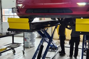 Red electric car on lift at Garage-EV vehicle service center in Dartmouth.