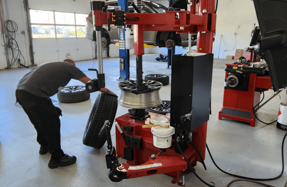 Technician changing tire on electric vehicle at Garage-EV service center.