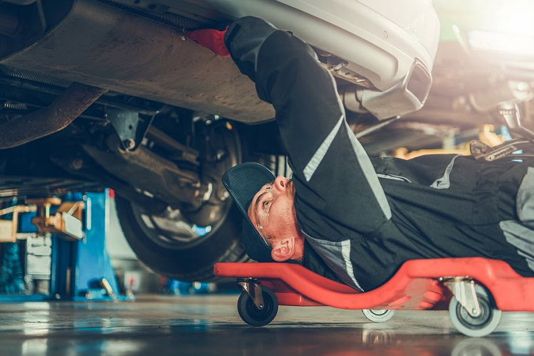 Technician inspecting undercoating of an electric vehicle in a service center.