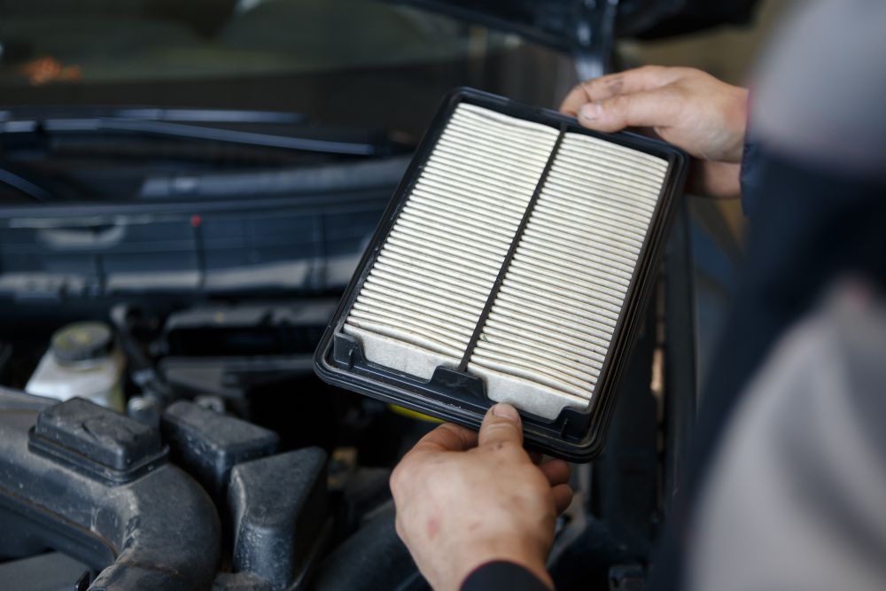Person replacing air filter in electric vehicle engine bay in Dartmouth.