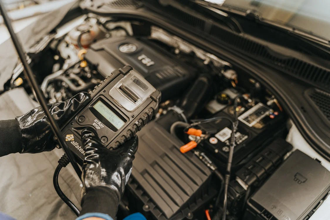 Technician testing electric vehicle battery with diagnostic tool.
