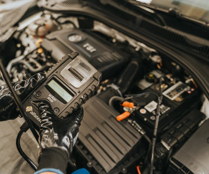 Technician testing electric vehicle battery with diagnostic tool.