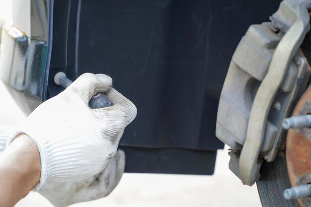 Technician inspecting vehicle undercoating with a tool.
