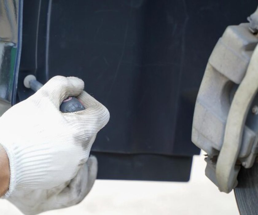 Technician inspecting vehicle undercoating with a tool.