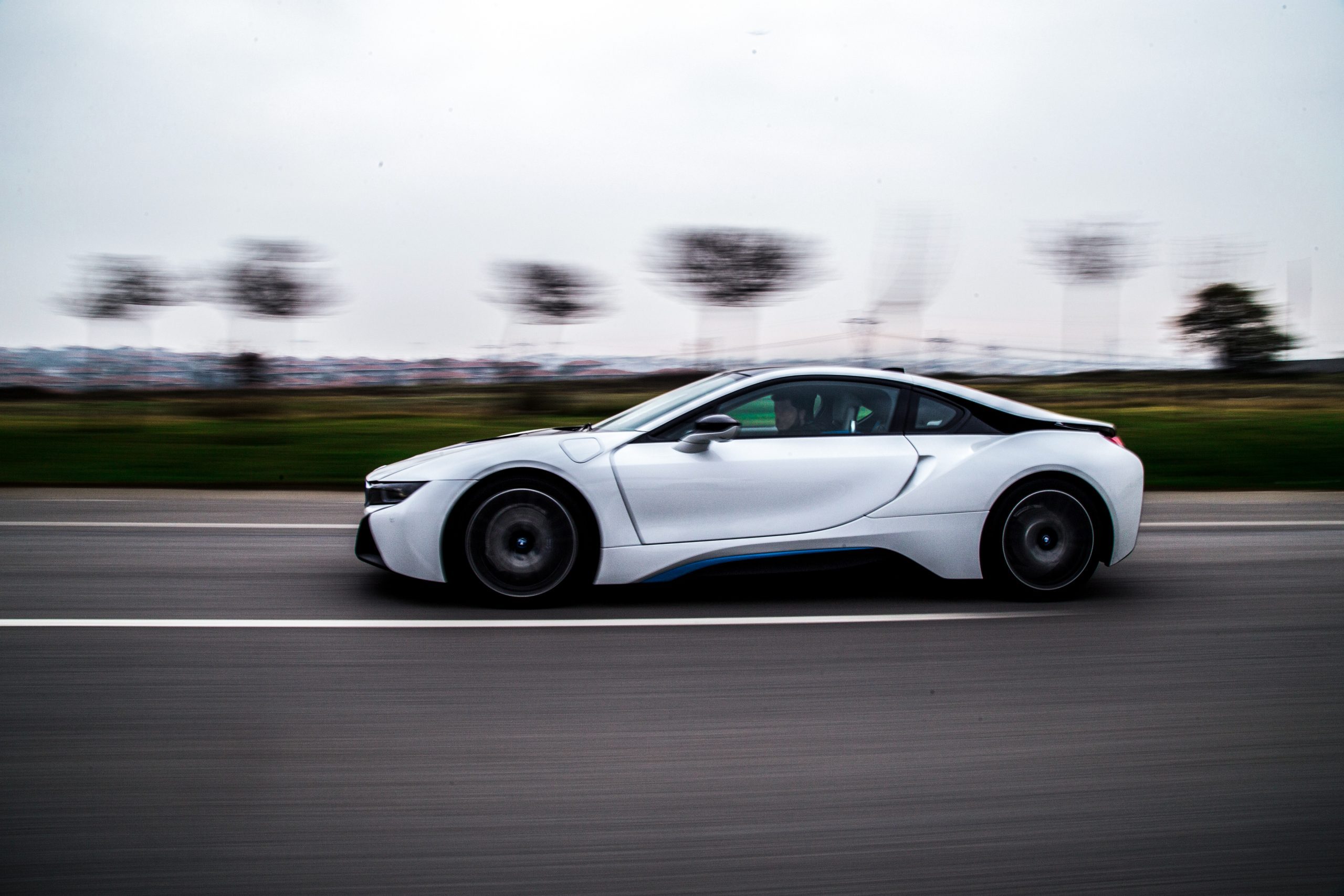 White electric sports car driving on highway with blurred background.