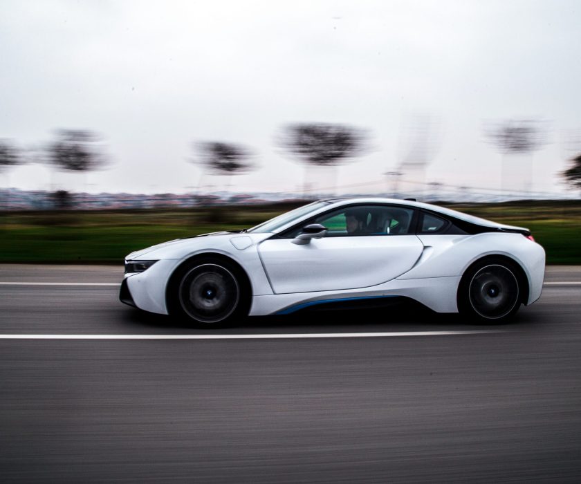 White electric sports car driving on highway with blurred background.