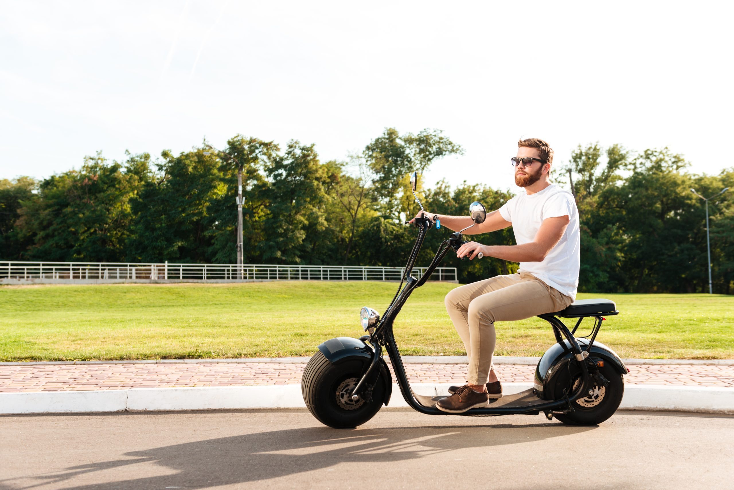 Man riding an electric scooter on a sunny day in a park.