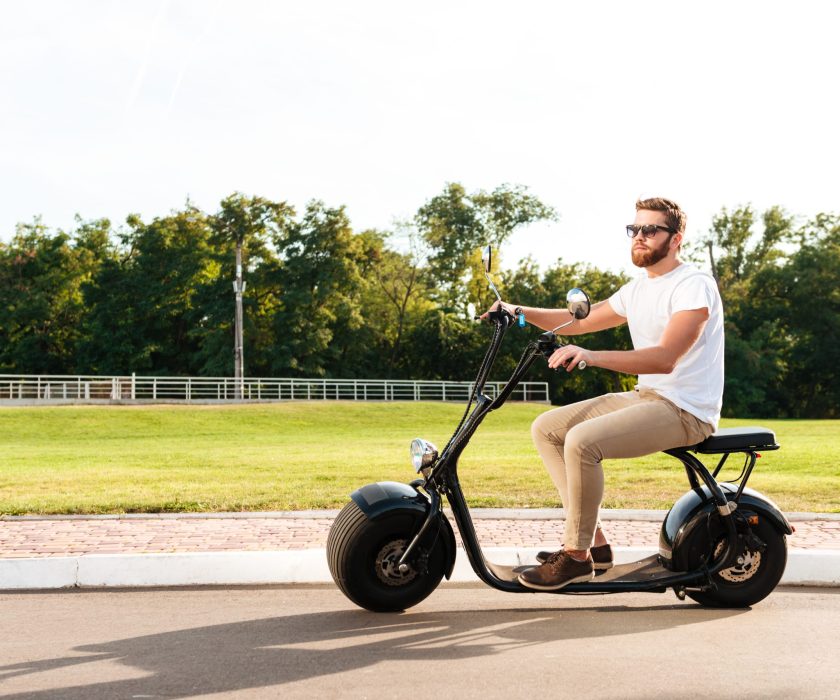 Man riding an electric scooter on a sunny day in a park.