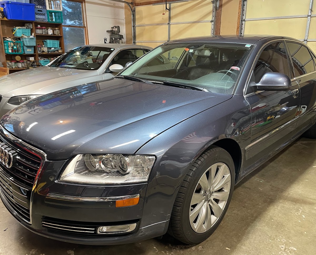 Luxury Audi A6 sedan parked indoors with other vehicles and tools in the background.