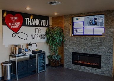 Healthcare workers appreciation wall at Global Car Care with thank you message and fireplace.