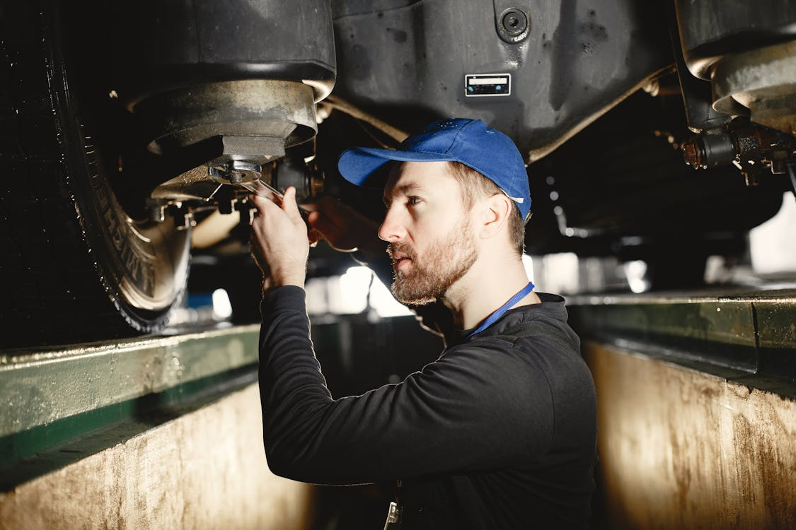 Man inspecting under a hot rod for maintenance and performance checks.