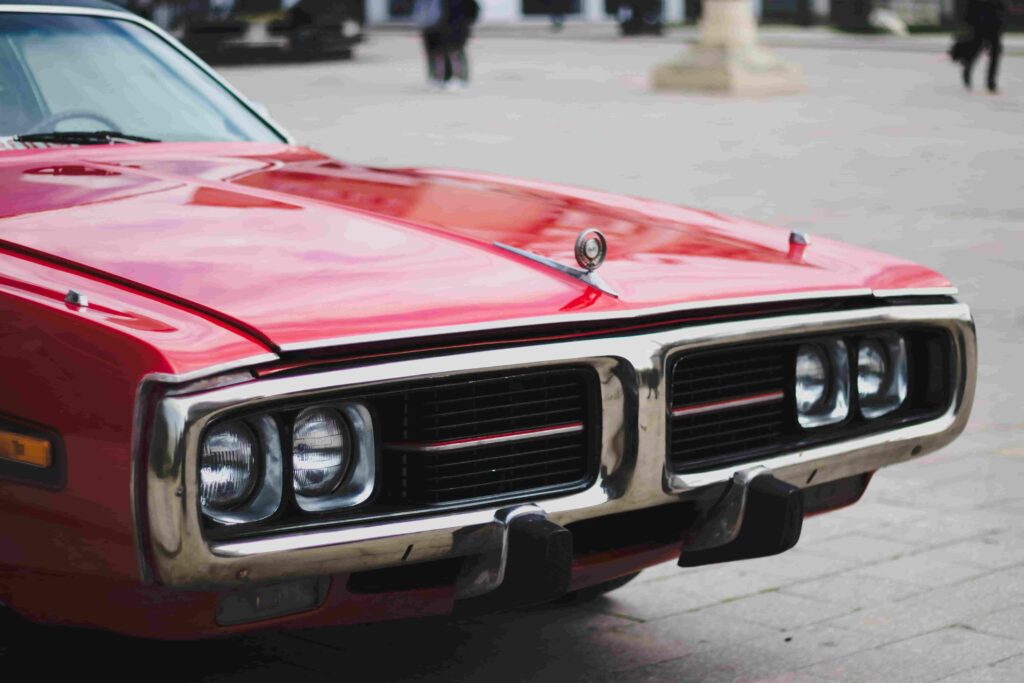 Vintage muscle car front with bold grille and dual headlights.
