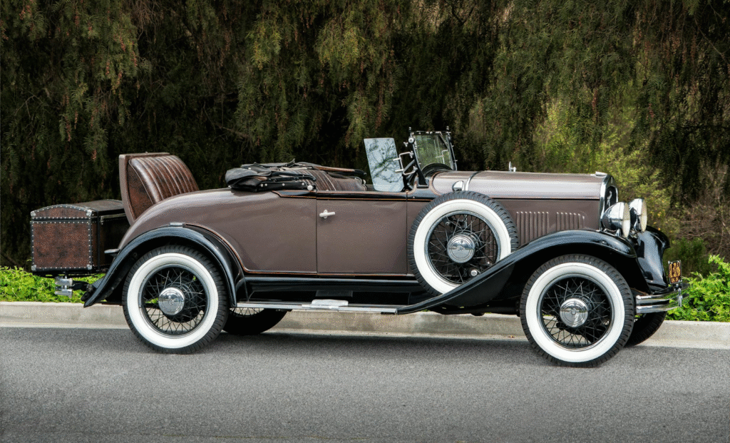 Vintage classic car with elegant design and whitewall tires on a scenic road.