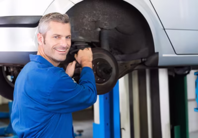 male-mechanic-servicing-brake-rotor-suspension-lifted-silver-car-garage-copy-space