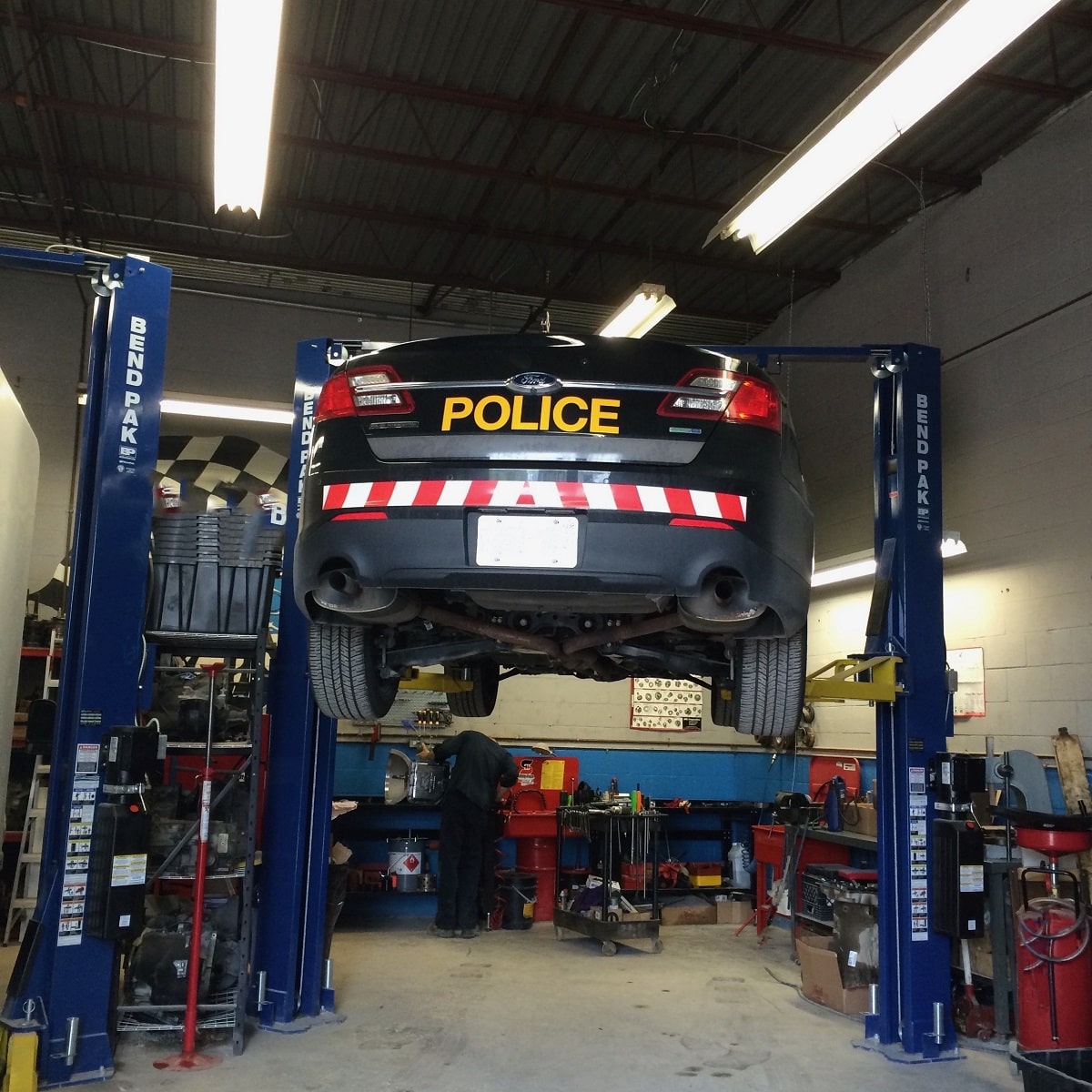 Police car lifted on a hydraulic lift in an auto repair shop.