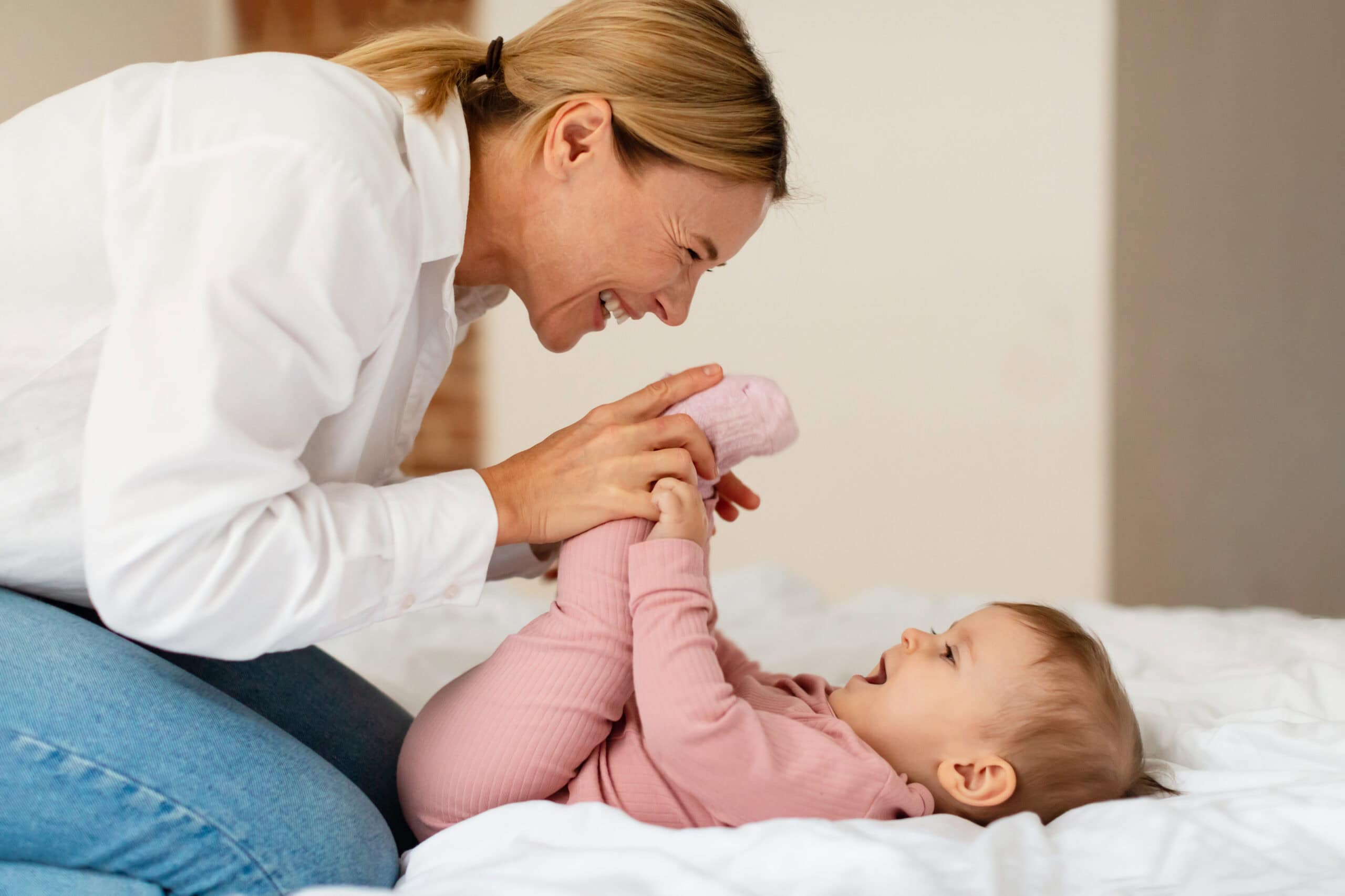 Happy woman playing and bonding with infant.
