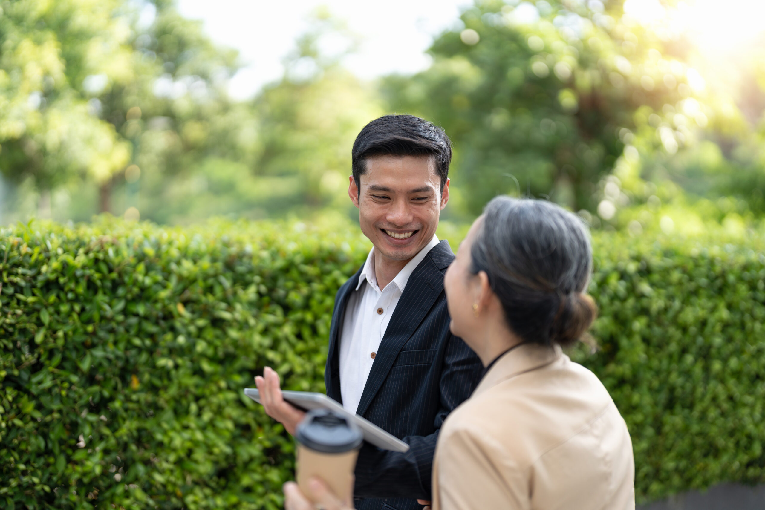 Portrait of young and senior business people working together with digital tablet outdoor.