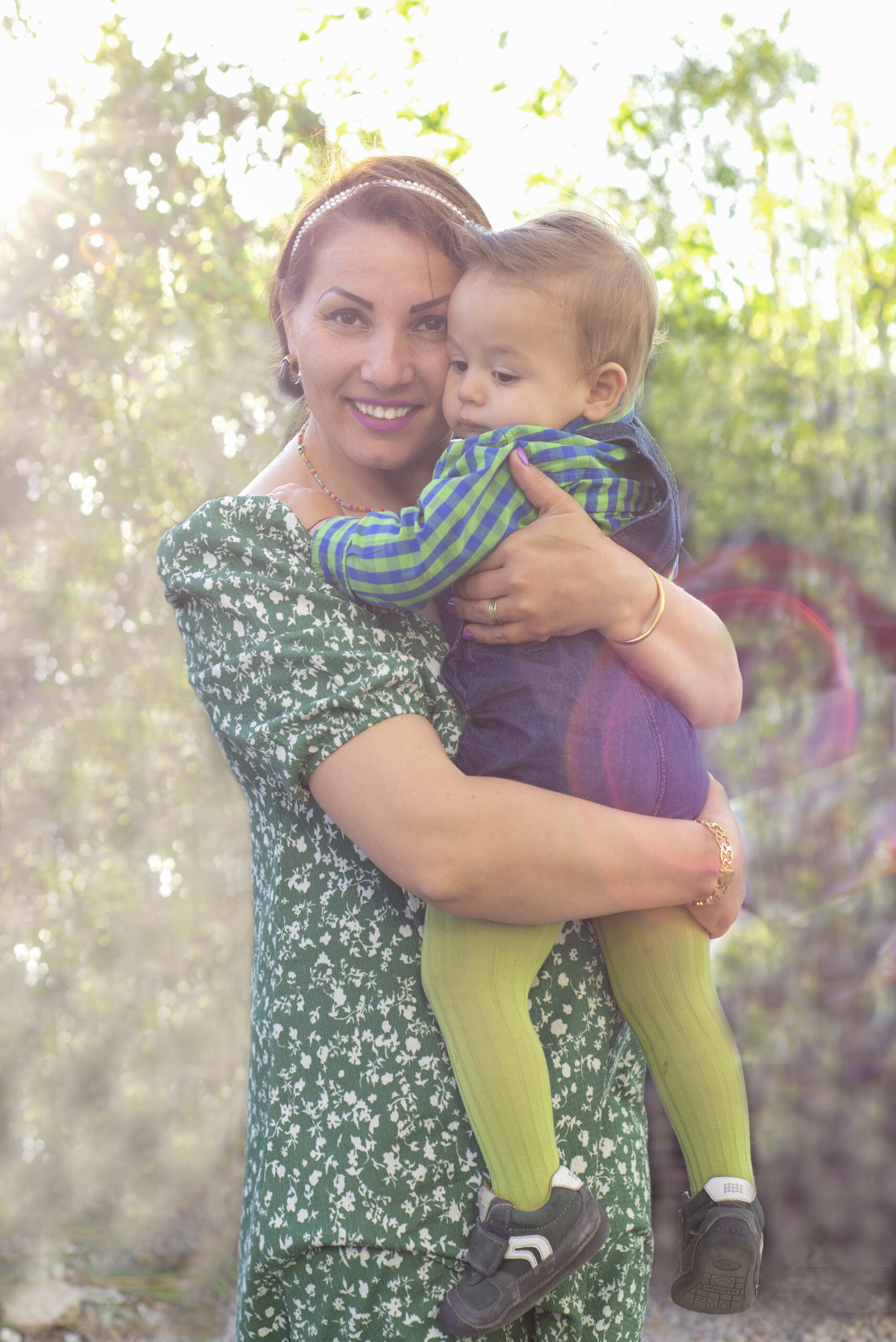 A happy mother hugs and holds the baby in her arms, laughs and presses it to her cheek, back rays of the setting sun. Concept for mother's day and international children day