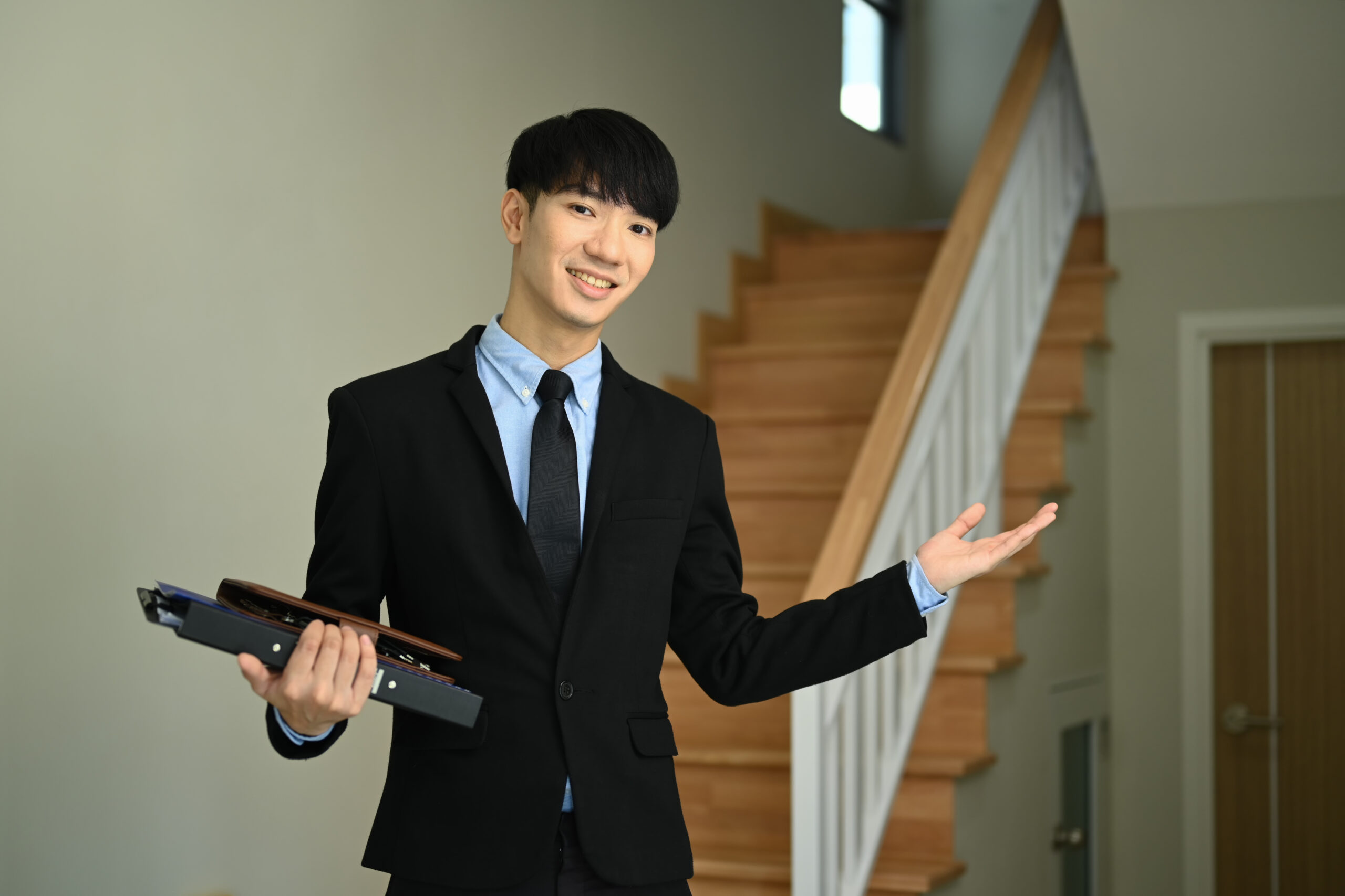 Confident male realtor standing in new house for sale ready to presenting offer. Real estate and property investment concept