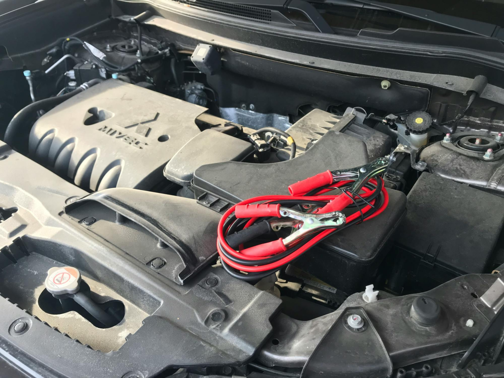 Engine bay with jumper cables ready for car battery service.