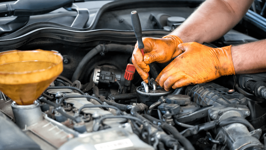 Technician performing engine repair with tools under the hood.