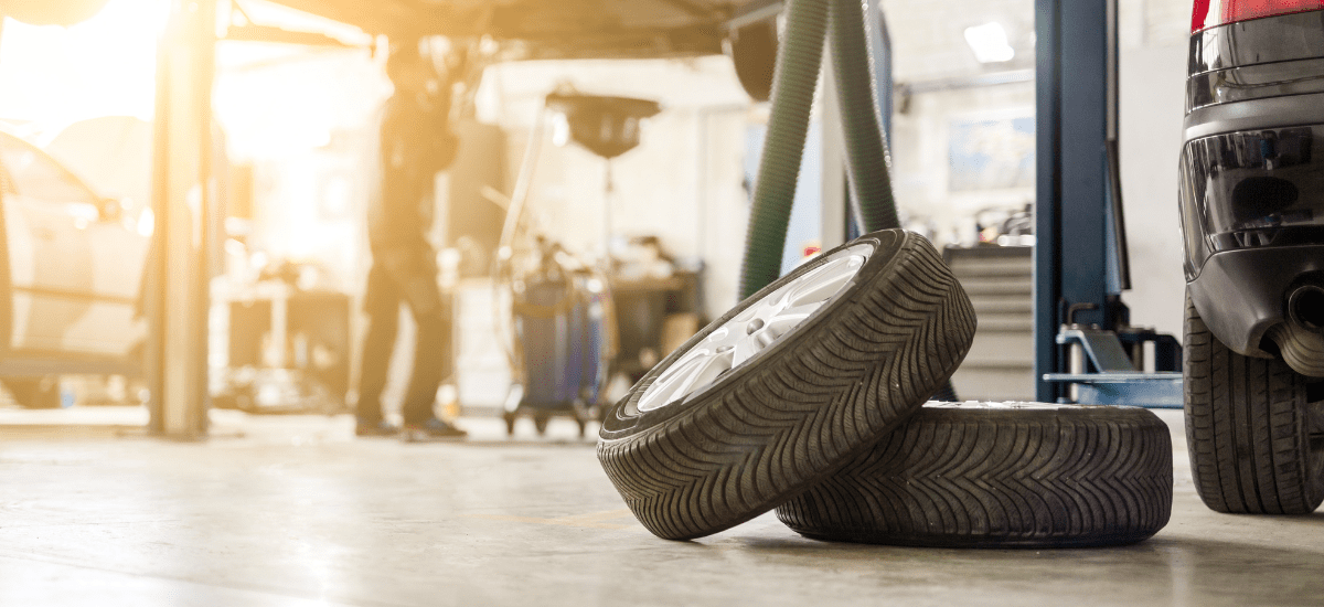 Car tire being replaced at auto repair shop in a modern garage setting.